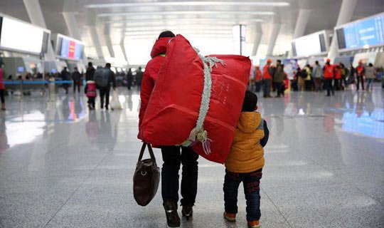 1月16日,杭州火车东站,一位母亲背着沉重的包裹带着孩子回家.时鹏 摄