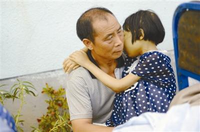 女孩小婷抱着父亲，患病的她没有精神，连抱住父亲都很勉强。